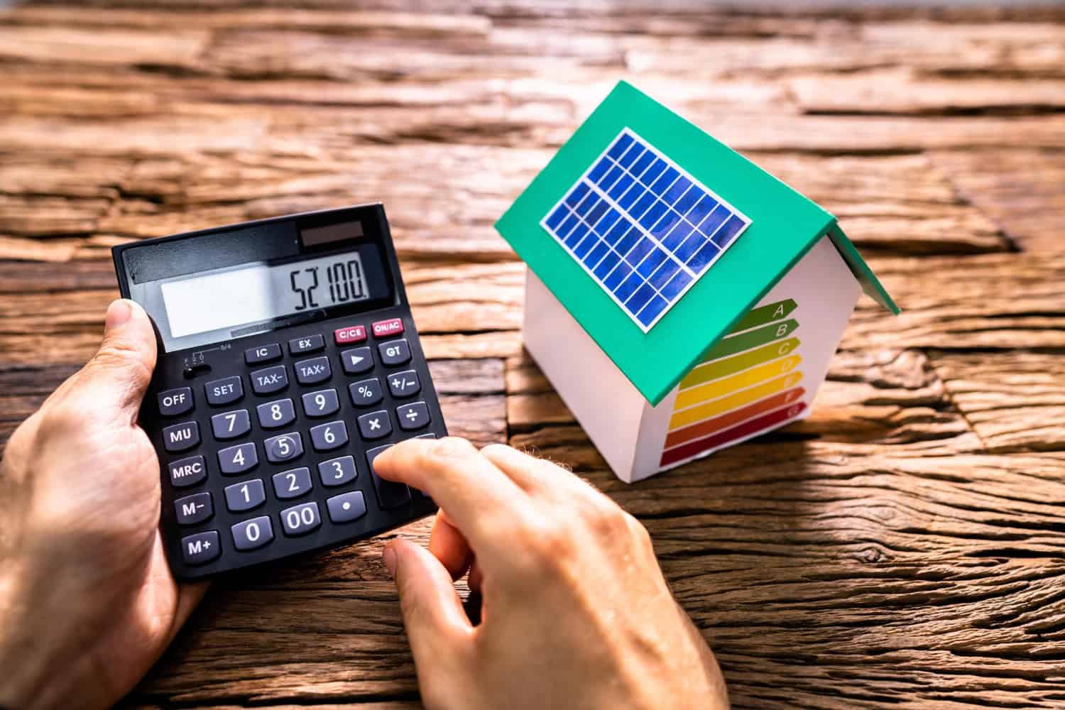 Grafika nawiązuje do obliczania rachunku za energię, widać na niej kalkulator i budynek energooszczędny. Bon energetyczny pomoże gospodarstwom domowym w opłaceniu rachunków za prąd.