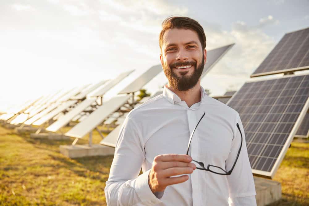 Mężczyzna, prosument energii, na tle paneli fotowoltaicznych